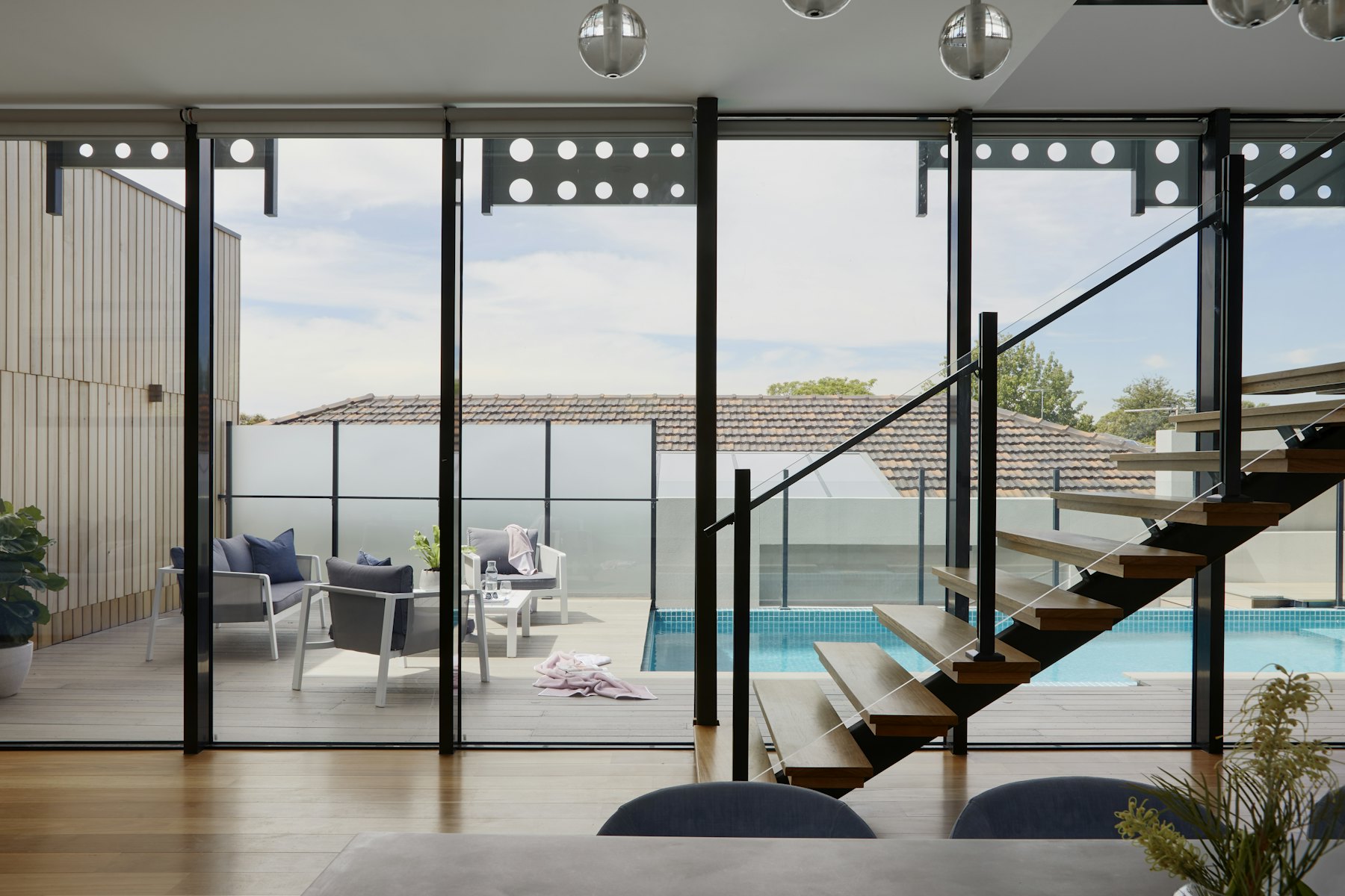 Glass-walled living space opening onto a pool terrace