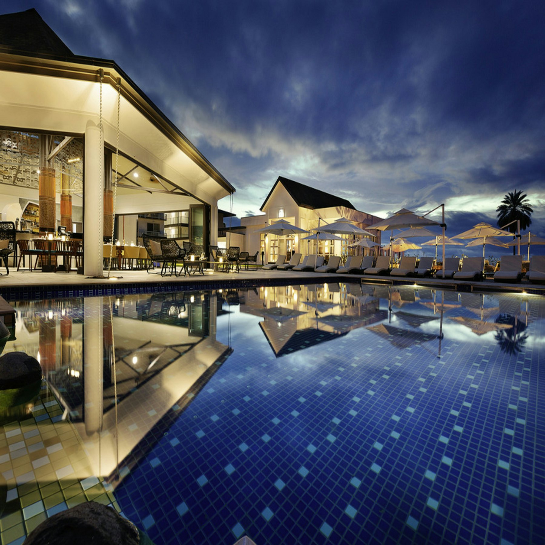 Infinity pool and pavilion illuminated at dusk